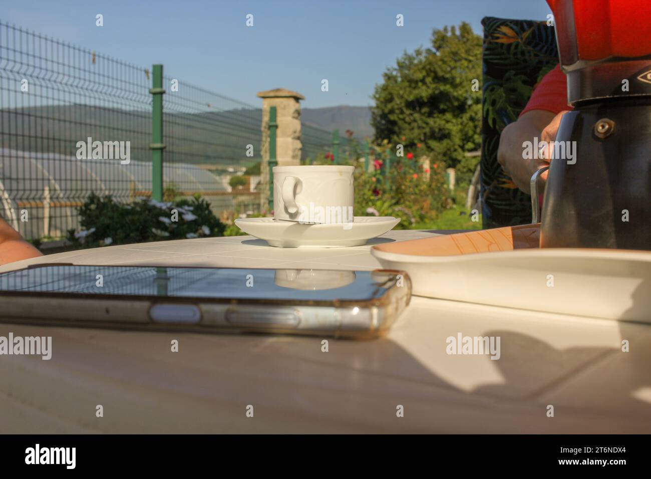 uno smartphone mobile su un tavolo mentre una donna sta bevendo un caffè Foto Stock