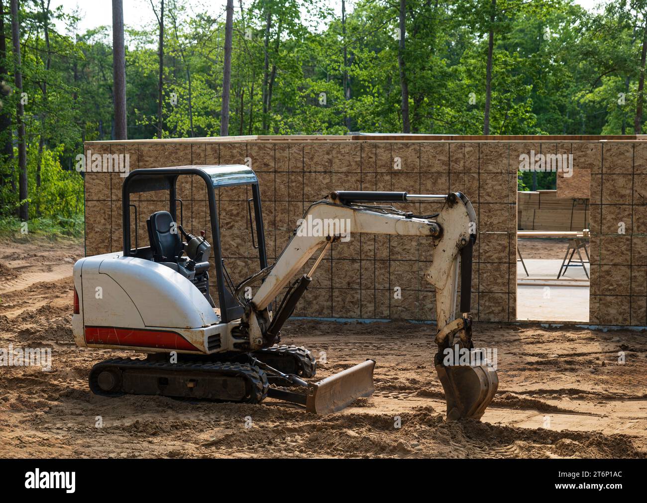 Miniescavatore parcheggiato sullo sporco all'esterno di un nuovo progetto di costruzione di un cantiere. Foto Stock