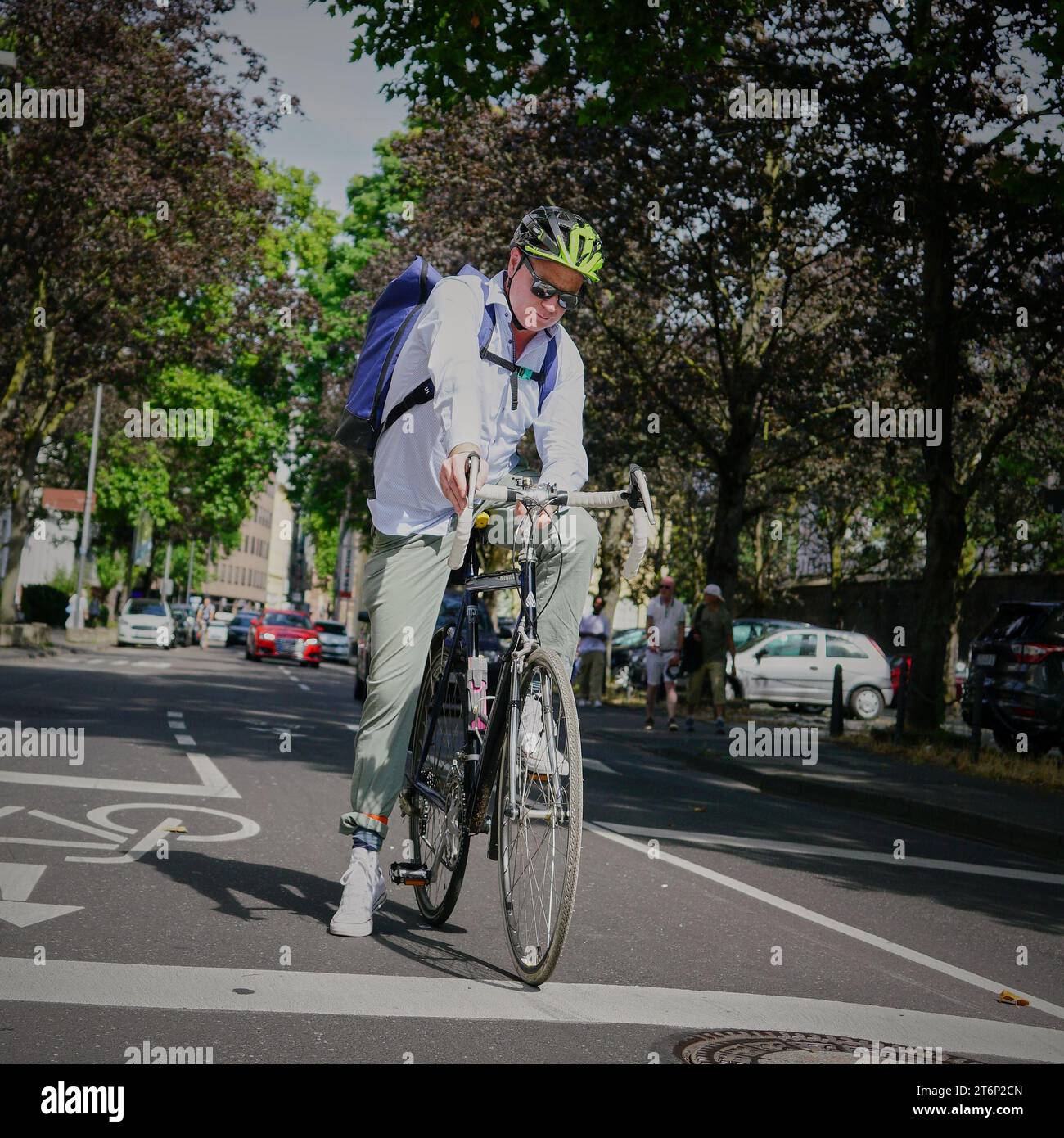 Uomo pendolare sulla sua bici in attesa al semaforo di una strada nel centro di Colonia, Germania. Pendolari ecologici. Foto Stock