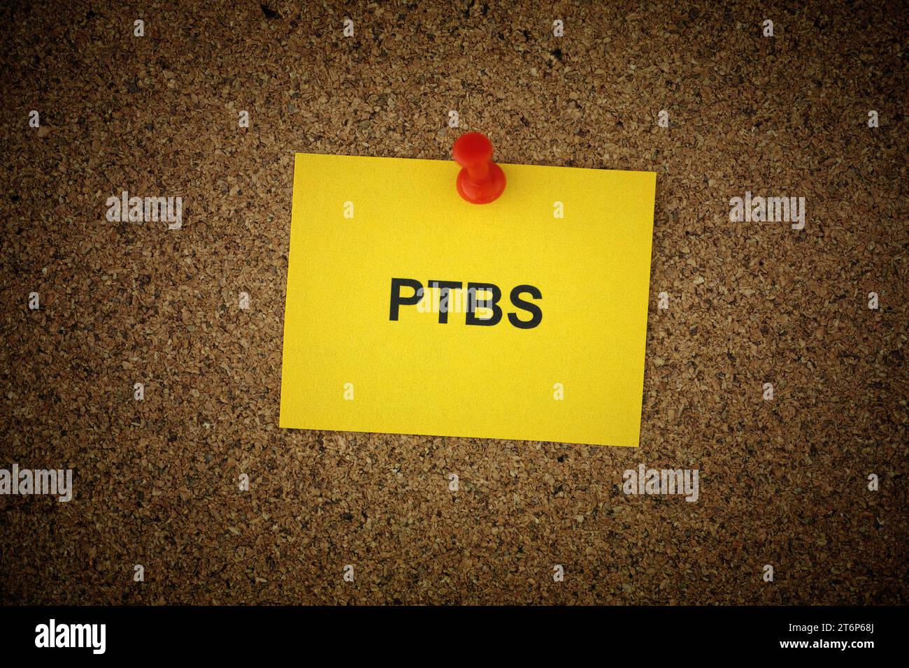 Una nota di carta gialla con l'abbreviazione PTBS - disturbo da stress posttraumatico (in tedesco) apposta su di essa su una tavola di sughero. Primo piano. Foto Stock