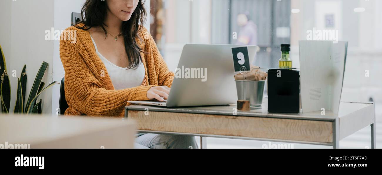 Ritaglia donna che usa un laptop Cafe Foto Stock