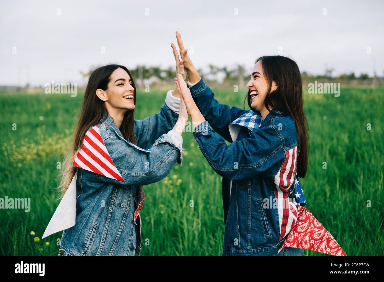 Amiche femminili che ridono l'erba con attributi americani Foto Stock