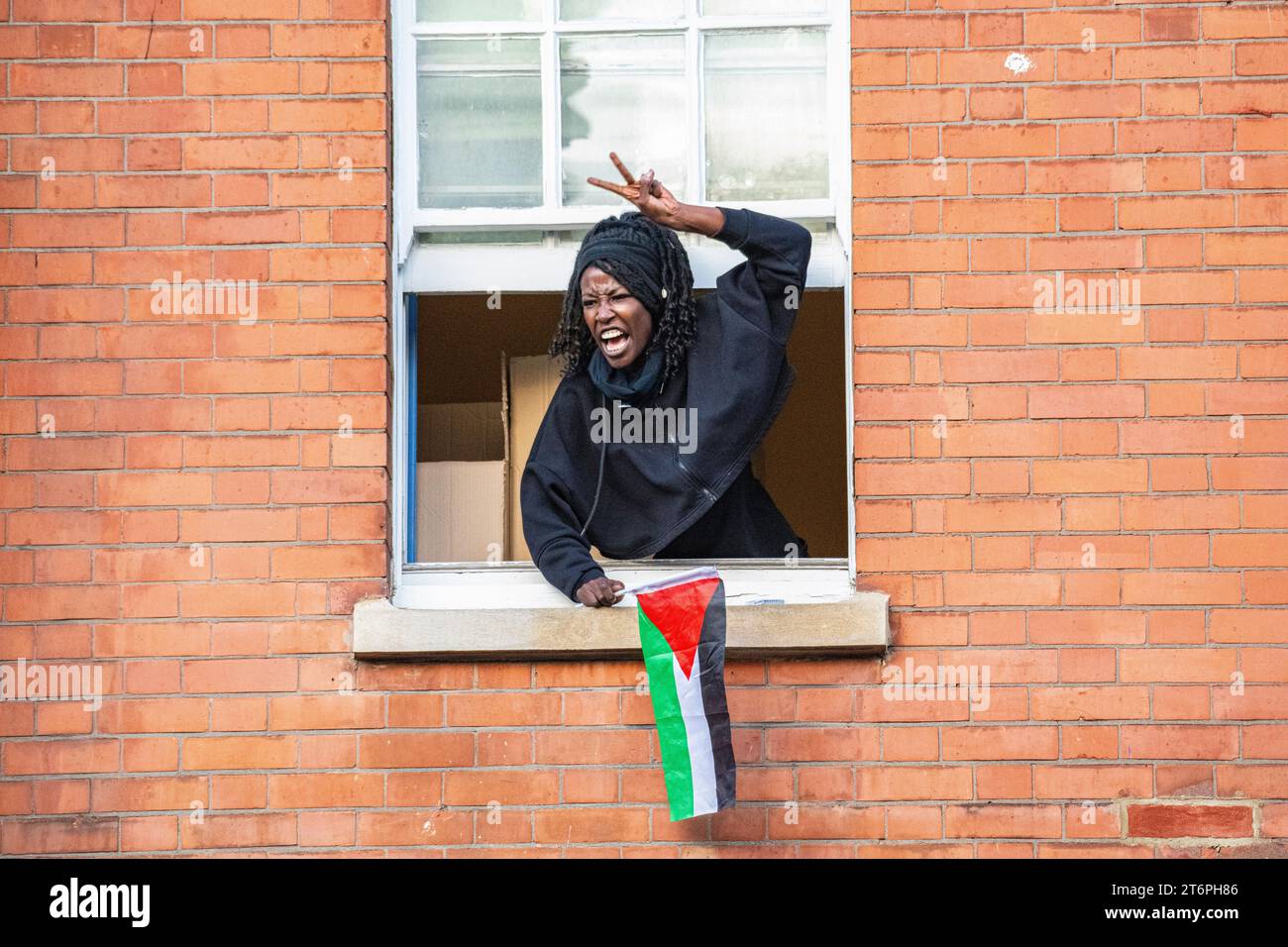 Londra, Regno Unito, 11 novembre 2023. Una donna grida dalla sua finestra a 300.000 sostenitori della Palestina che marciano attraverso Londra Foto Stock