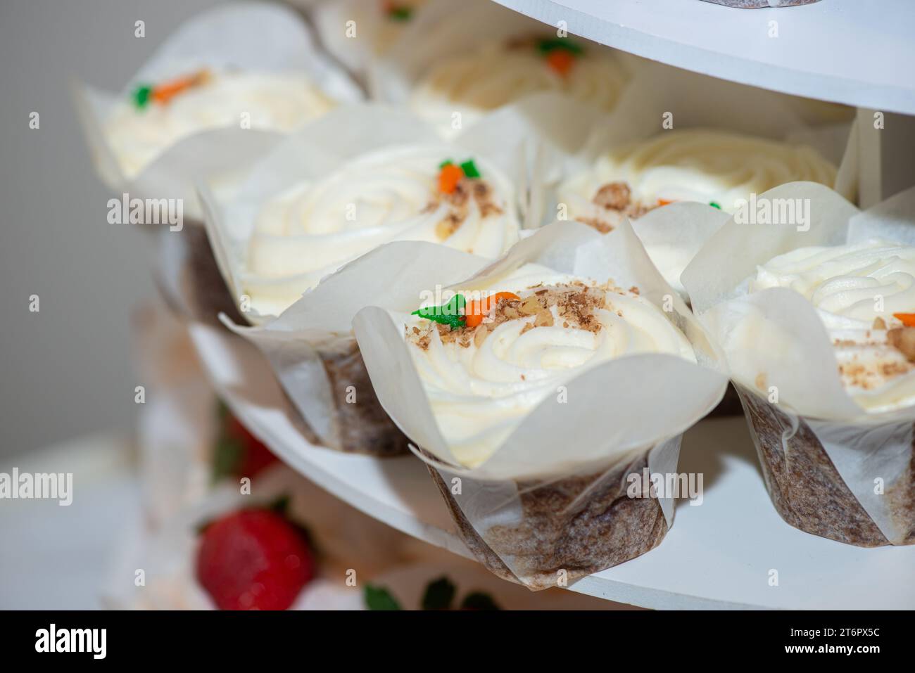 Torte di cioccolato con turbolenza di rasberry e frutta di rasberry su cupcake con glassa alla vaniglia e condimenti di carote sul tavolo del dessert Foto Stock