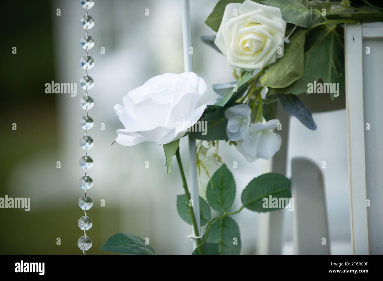 Splendido decor di rose bianche con cristalli su sedie bianche durante la romantica cerimonia di nozze isle Foto Stock