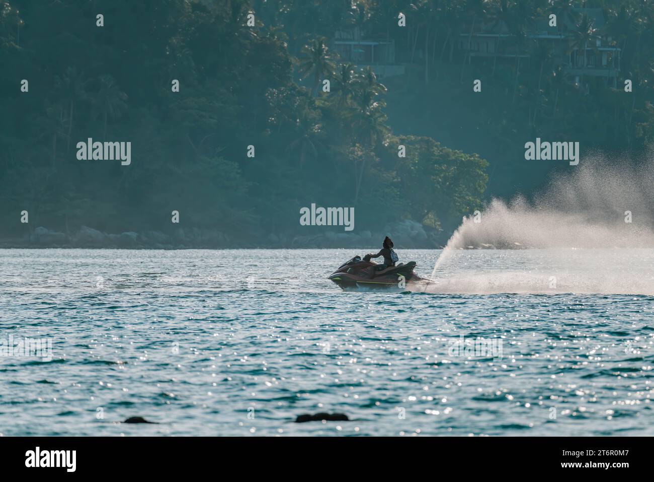 Donna nera a guida veloce in moto d'acqua sul mare scintillante. Foresta tropicale sfocata, foto ravvicinata Foto Stock