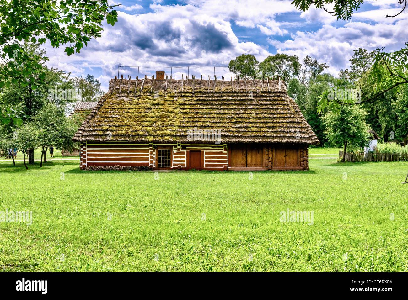 Un frammento di una tradizionale casa polacca con un tetto di paglia e una porta di legno dipinta in stile nazionale. Foto Stock