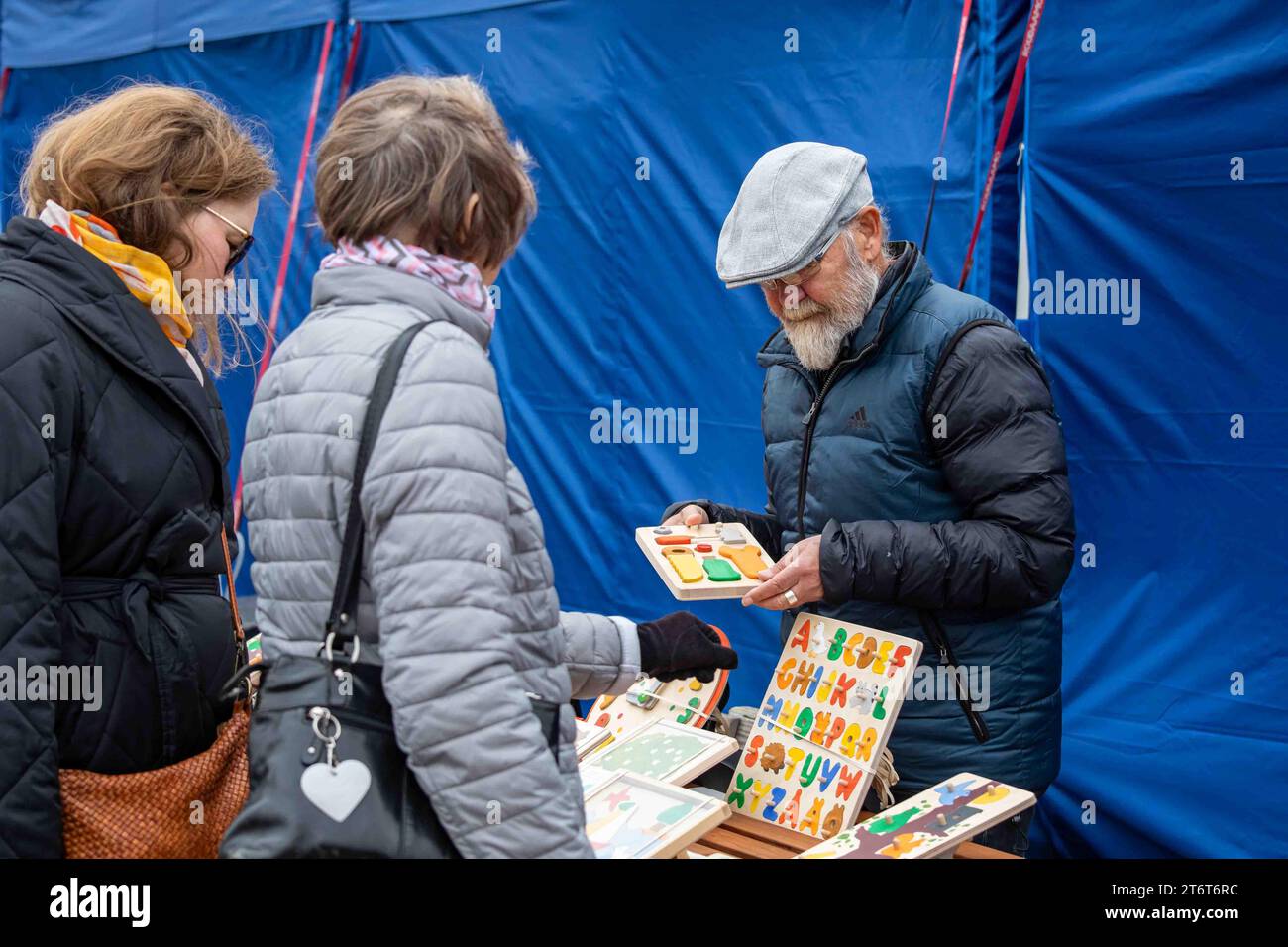 Uomo anziano che vende giocattoli in legno alla piazza del mercato di Helsinki, Finlandia Foto Stock