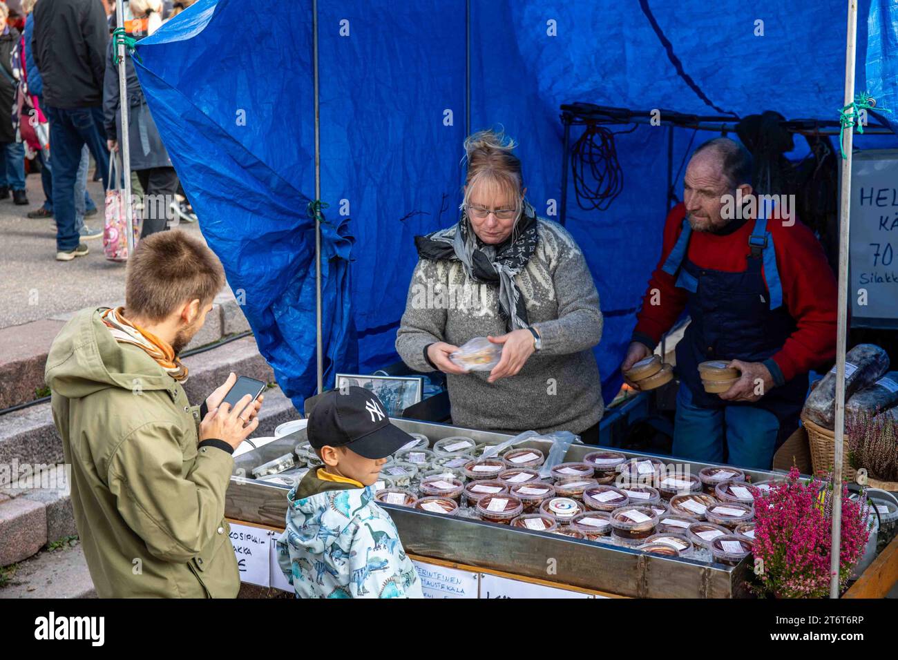 Venditori che vendono prodotti di aringhe baltiche da bancarelle di barche presso Piazza del mercato a Stadin silakkamarkkinat o Baltic Herring Fair a Helsinki, Finlandia Foto Stock