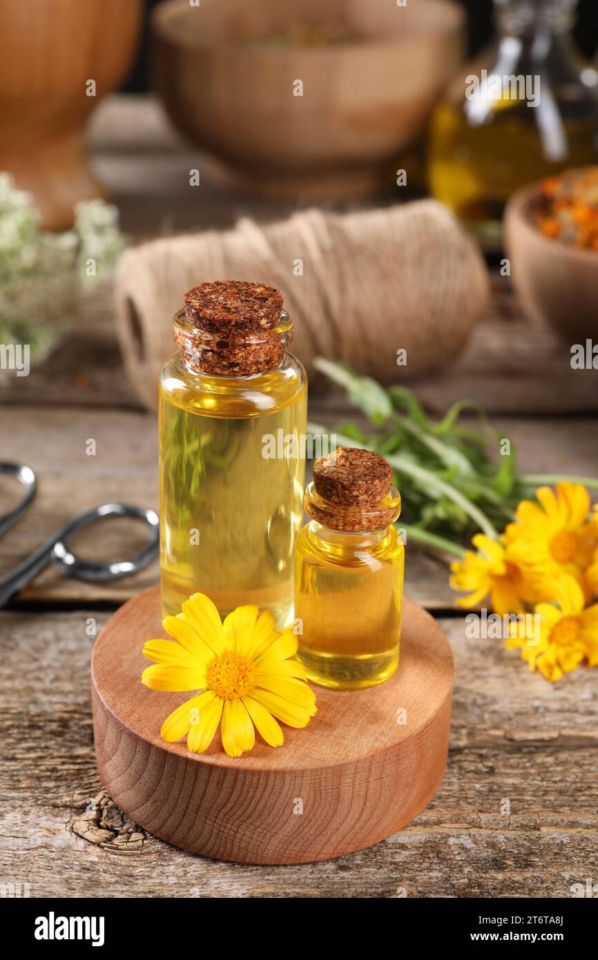 Bottiglie di oli essenziali e fiori di calendula su tavola di legno. Erbe medicinali Foto Stock