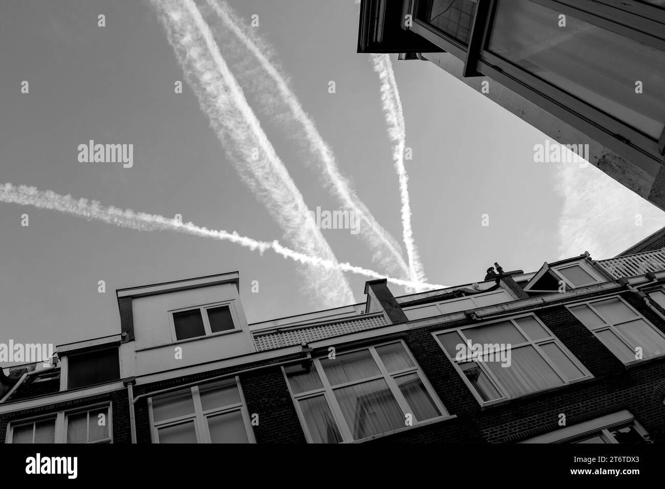 Fotografia in bianco e nero di Sky and Houses with Roofs and Traces from Jets or Plane, Netherland, the Hague. Foto Stock