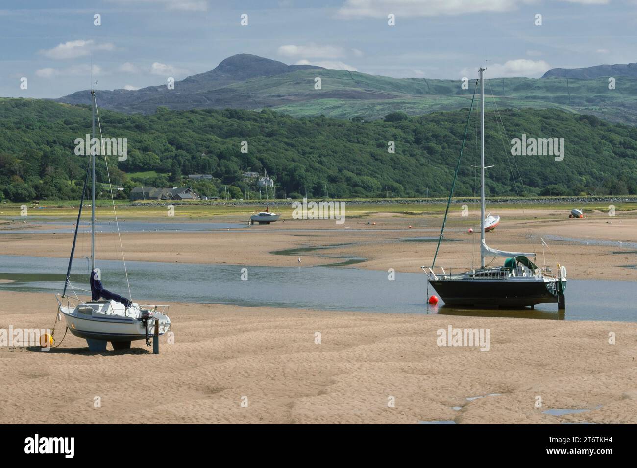 Le piccole barche a vela si siedono sulla sabbia e aspettano che arrivi la marea, ad Abersoch, nel Galles occidentale, Regno Unito Foto Stock