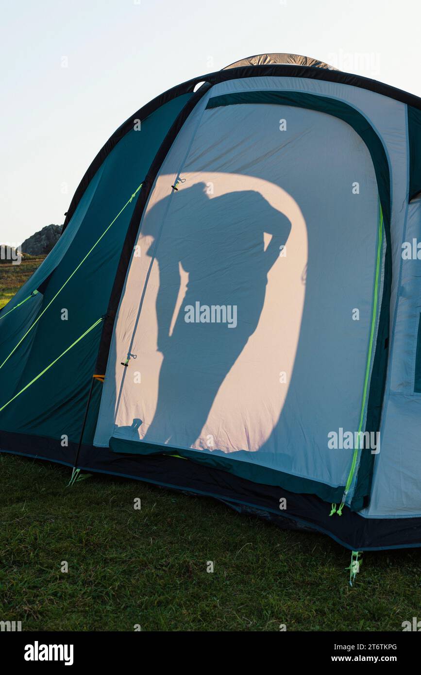La silhouette di una donna in una tenda in un campeggio in estate nel Galles occidentale, nel Regno Unito Foto Stock