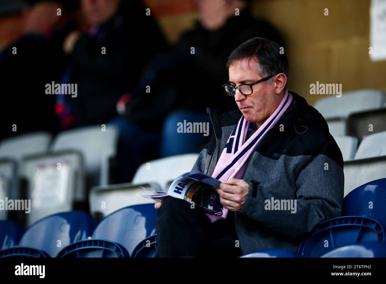 Una tifosa di Dulwich Amleto che legge il programma del giorno della partita in una partita femminile di Dulwich Amleto Foto Stock Una tifosa di Dulwich Amleto che legge il programma del giorno della partita in una partita femminile di Dulwich Amleto Foto Stock