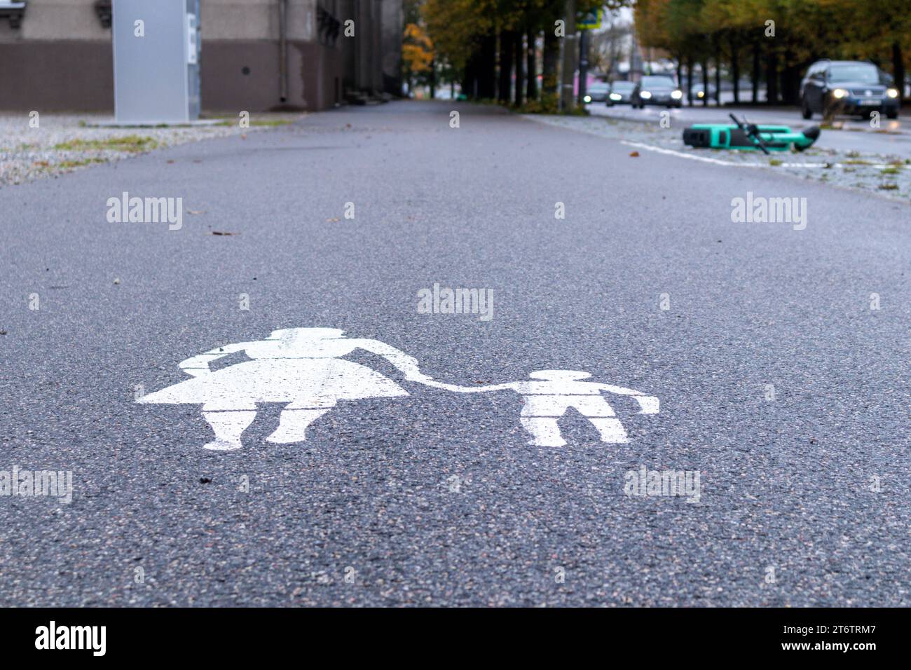 Segnaletica stradale pedonale sull'asfalto con uno scooter rovesciato sullo sfondo Foto Stock