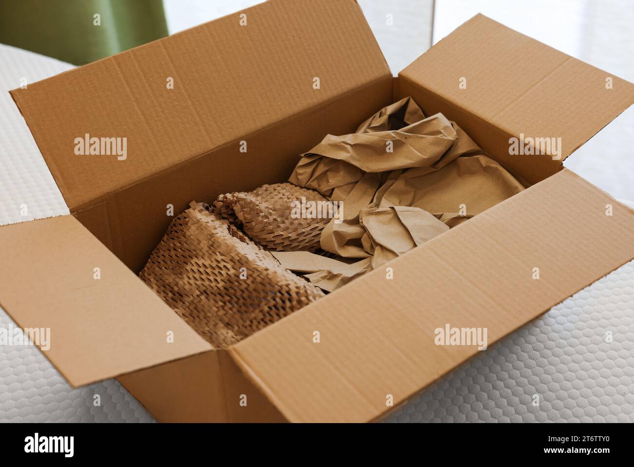 Scatola di cartone aperta con stucco di carta marrone schiacciata su materasso bianco Foto Stock
