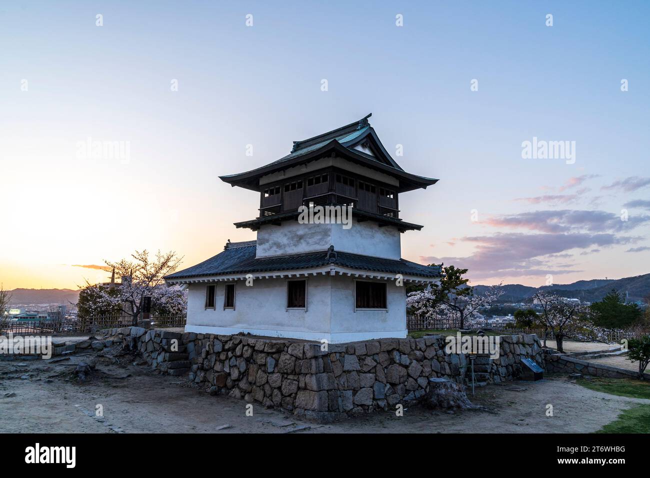 L'originale Shorou, torretta con campana, un importante patrimonio culturale, con fiori di ciliegio e tramonto al castello di Fukuyama durante la primavera in Giappone. Foto Stock