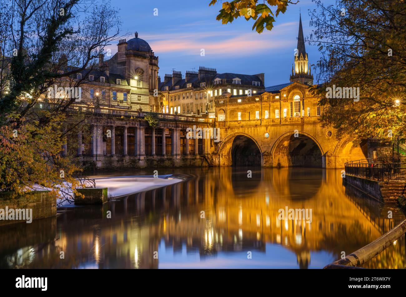 Bath, Somerset, Inghilterra. In una fredda sera di novembre, al crepuscolo, le luci lampeggiano nella splendida città di Bath. Pulteney Bridge si trova sopra il Ri Foto Stock