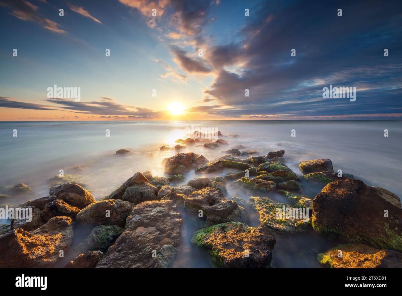 Splendido paesaggio nuvoloso sul mare e sulla costa rocciosa all'alba Foto Stock