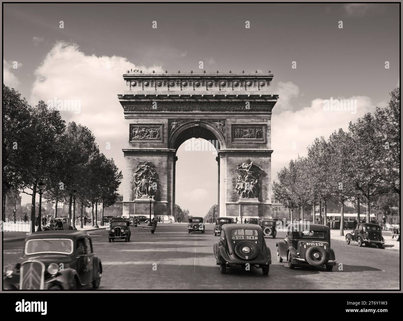 PARIGI vintage anni '30 retrò Parigi 1936 Arc de Triomphe e il traffico sugli Champs-Elysees tra cui Parigi Renault Taxi e persone che indossano gli stili e la moda del giorno. Pre WW2 Street scene archivio francese B&W fotografo Willem van de poll Foto Stock