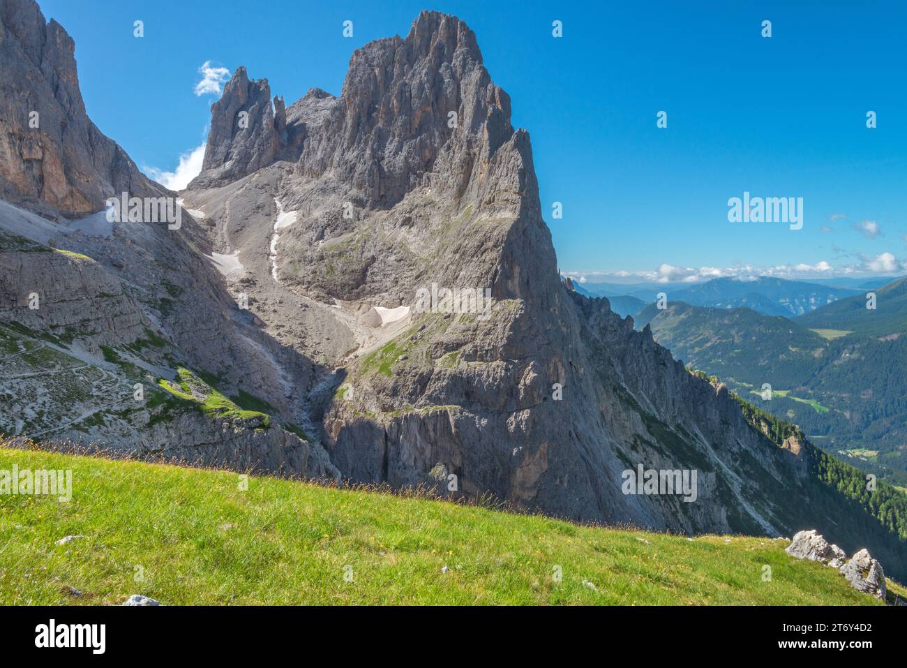 Ripido e affilato crinale di montagna che torreggia sopra il sentiero escursionistico. Trekking alpino nelle Dolomiti. Prato erboso e paesaggio montano. Foto Stock