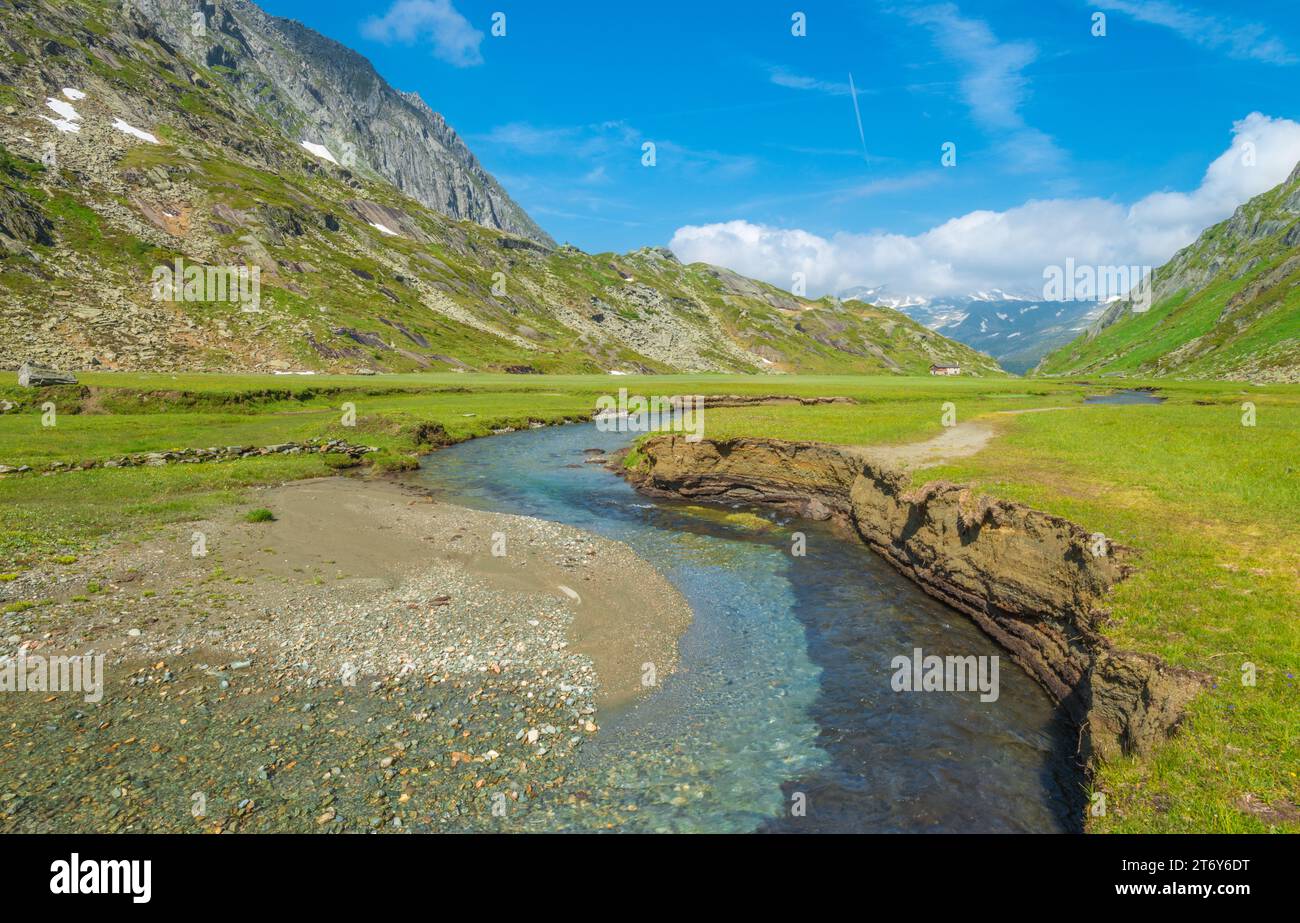 insenatura glaciale incontaminata che scolpisce e che eroga le rive del fiume in una lussureggiante valle alpina. Erosione dell'acqua al lavoro in montagna. Foto Stock