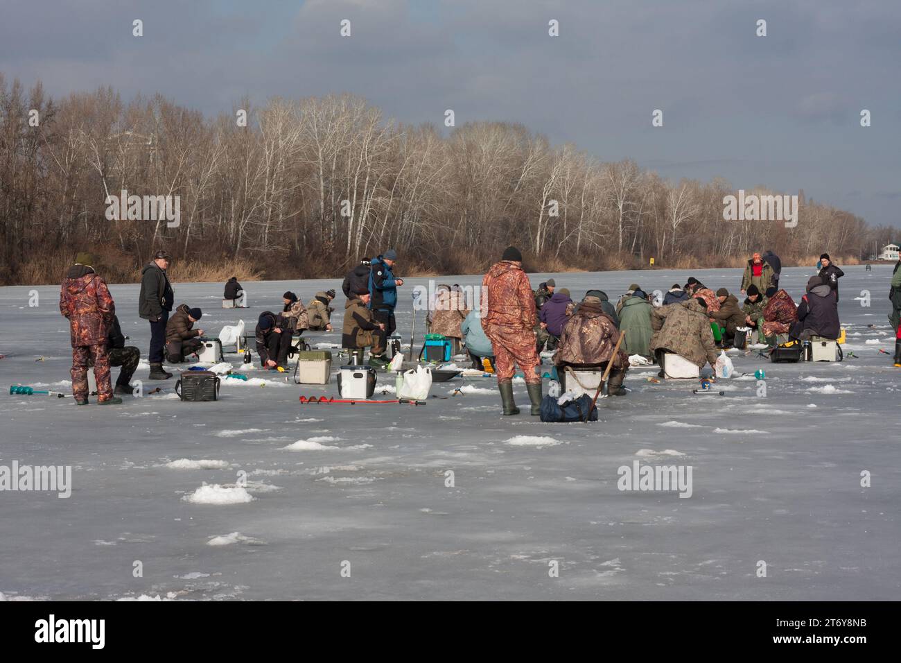 Dnipro, Ucraina - 9 febbraio 2022: Grande gruppo di pescatori sulla pesca invernale sul ghiaccio. Molte persone stanno pescando sul fiume coperto di ghiaccio. Giornata di sole. Wint Foto Stock