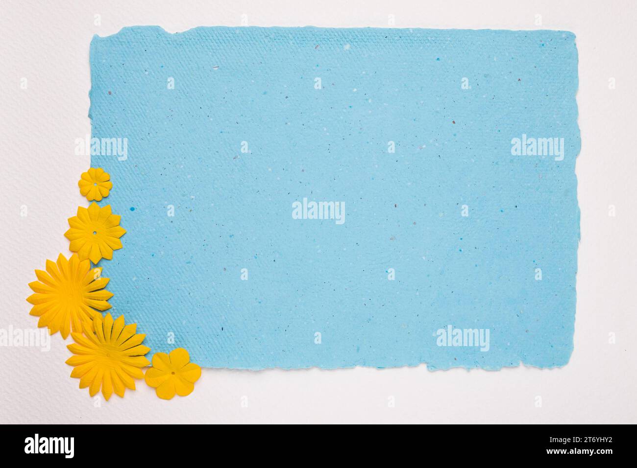 Carta blu con angoli gialli e fiori su sfondo bianco Foto Stock