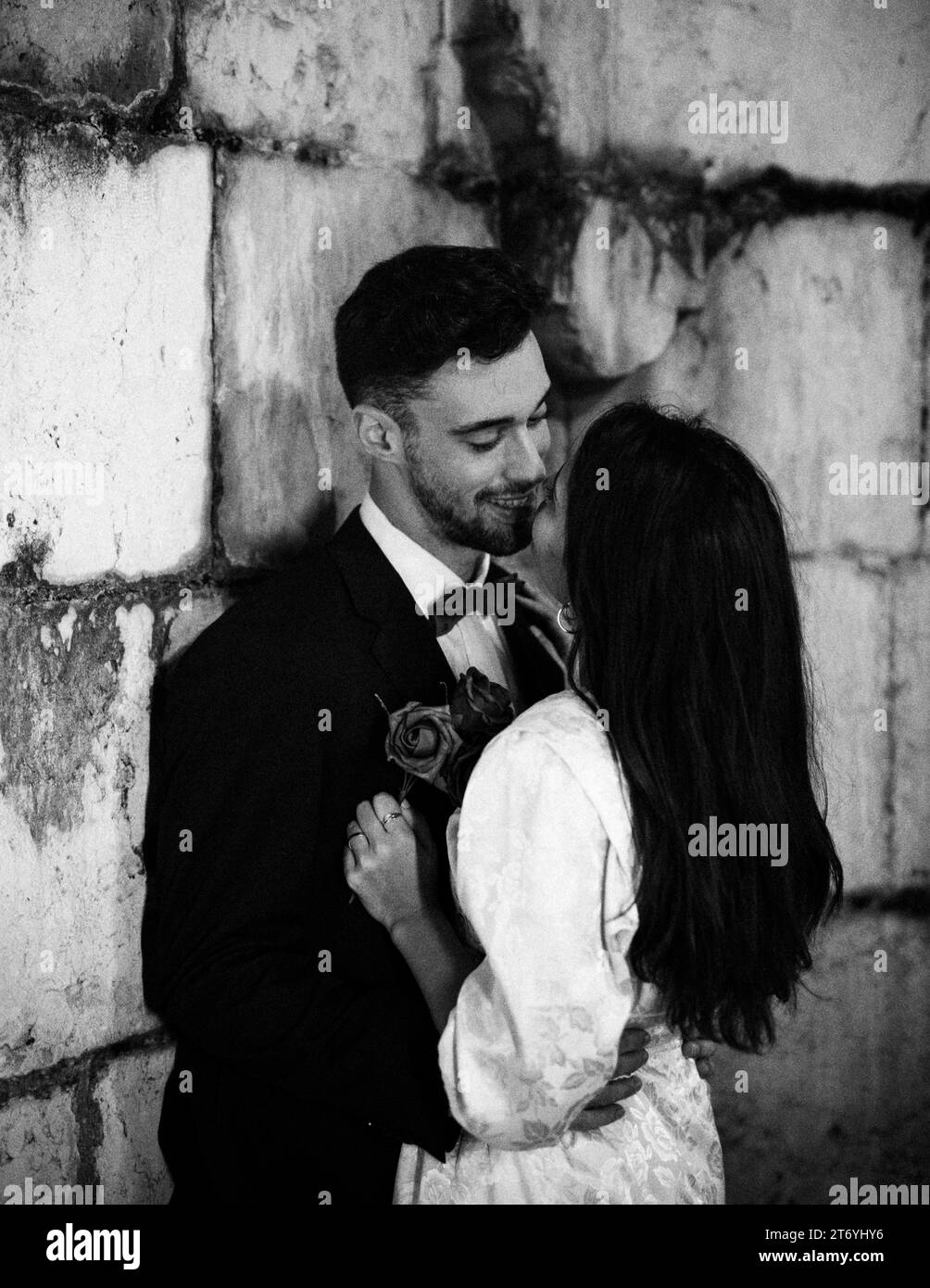 Giovane uomo che abbraccia una donna che si appoggia al muro Foto Stock