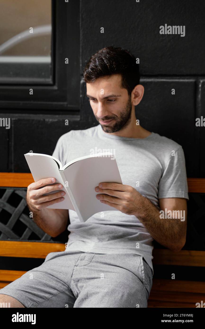 Uomo che legge un interessante banco di libri Foto Stock