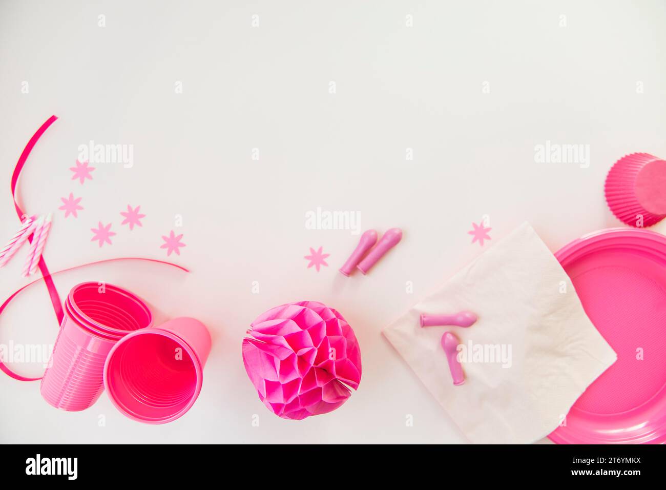 Candele rosa, bicchieri di plastica, piastre di carta, carta a nido d'ape, sfera di carta, sfondo bianco Foto Stock
