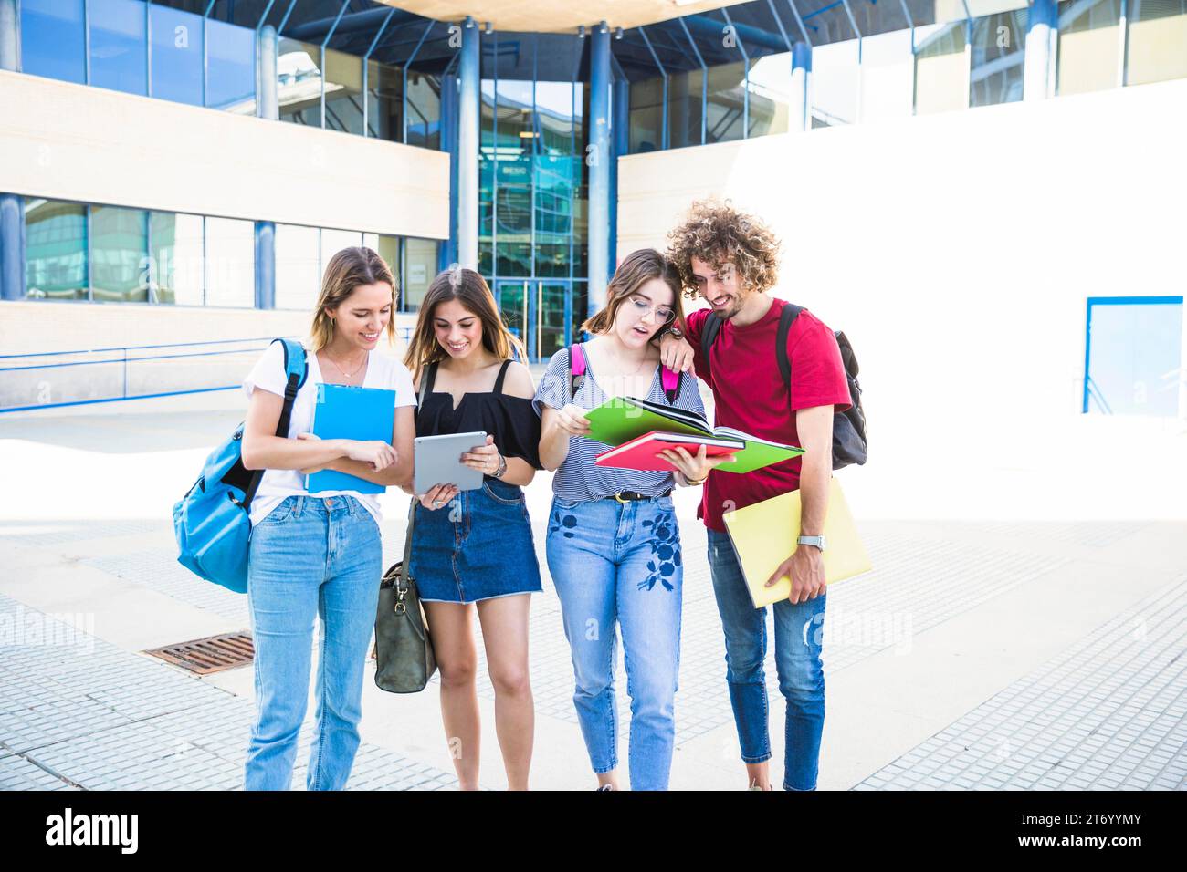 Studenti allegri con libri di testo in tablet vicino all'edificio universitario Foto Stock