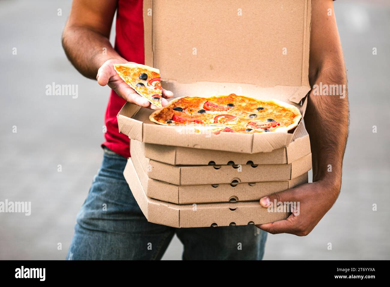 Primo piano, un addetto alla consegna che tiene una fetta di pizza Foto Stock