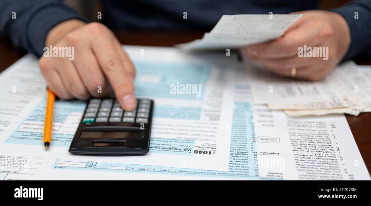Un uomo che organizza il modulo di dichiarazione dei redditi individuali 1040 e le ricevute. Sfondo sfocato. Ora imposta.Concept IVA. Primo piano. Foto Stock