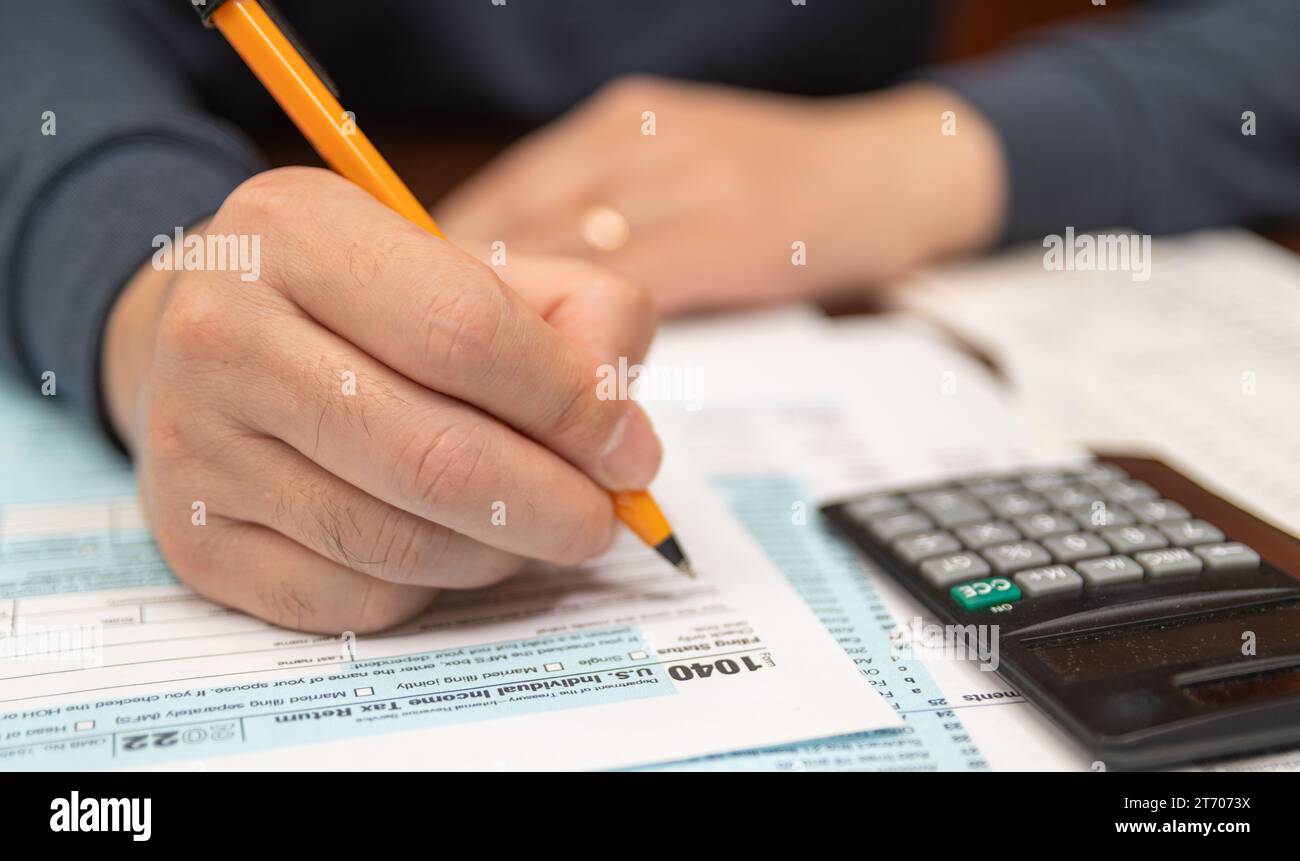 Un uomo che organizza il modulo di dichiarazione dei redditi individuali 1040 e le ricevute. Sfondo sfocato. Ora imposta.Concept IVA. Primo piano. Foto Stock