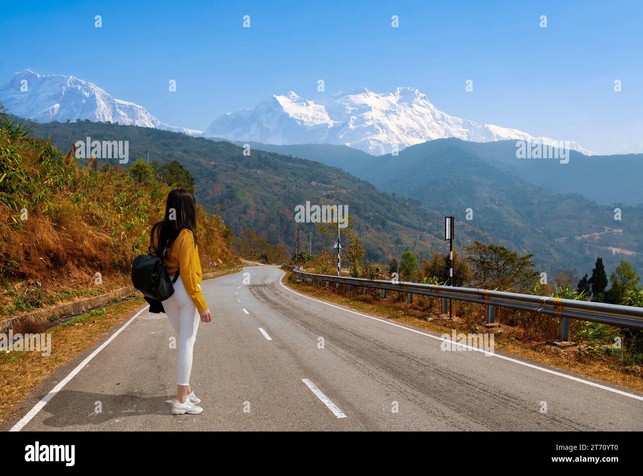 Turista femminile su strada autostradale con vista panoramica del paesaggio montano e della catena montuosa Kanchenjunga Himalaya sulla strada per Tinchuley, Darjeeling, India Foto Stock