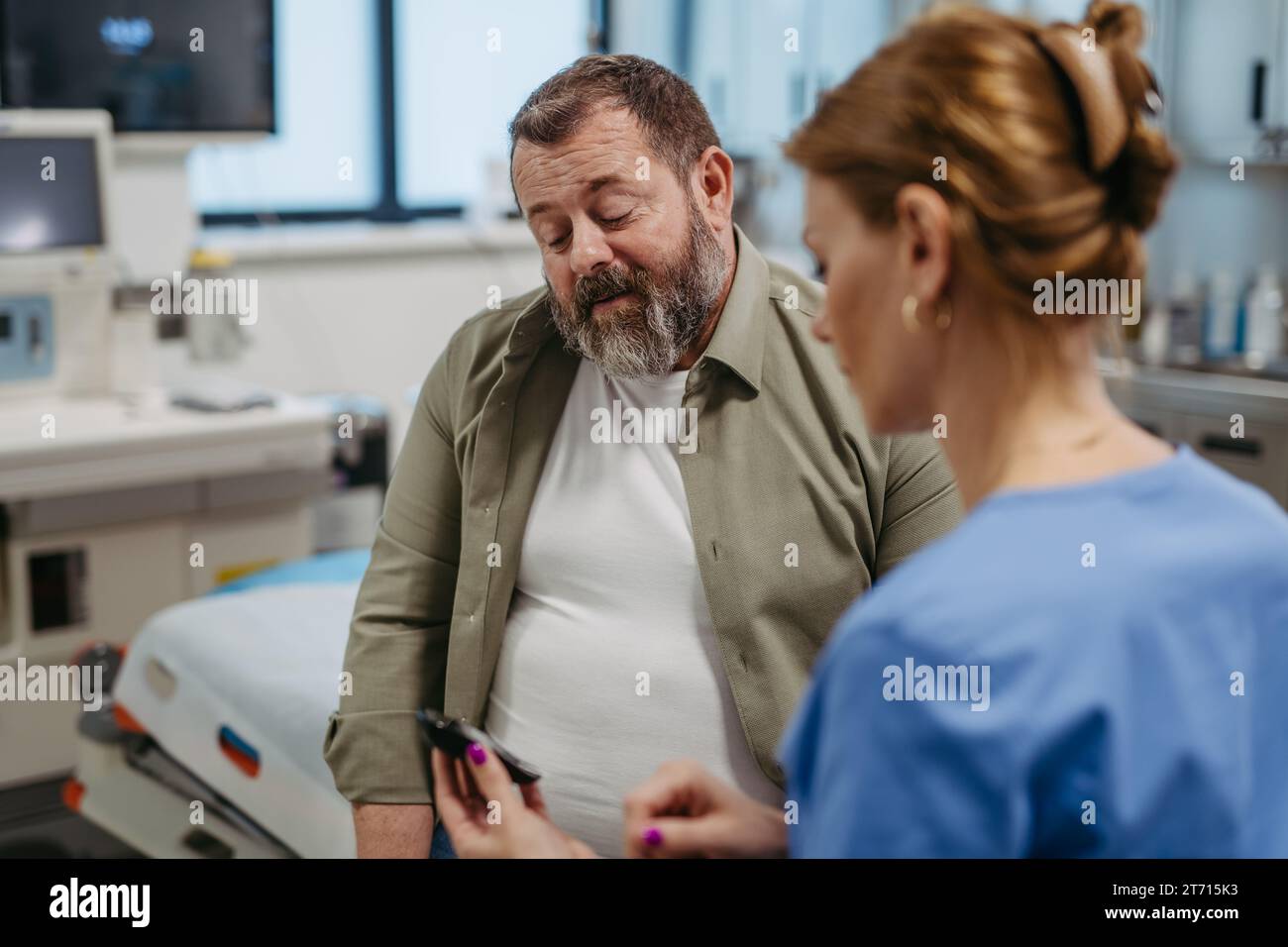 Controllo medico del livello di glucosio nel sangue con un glucometro a stick, in attesa dei risultati ottenuti dal glucometro. L'uomo obeso e sovrappeso è a rischio Foto Stock