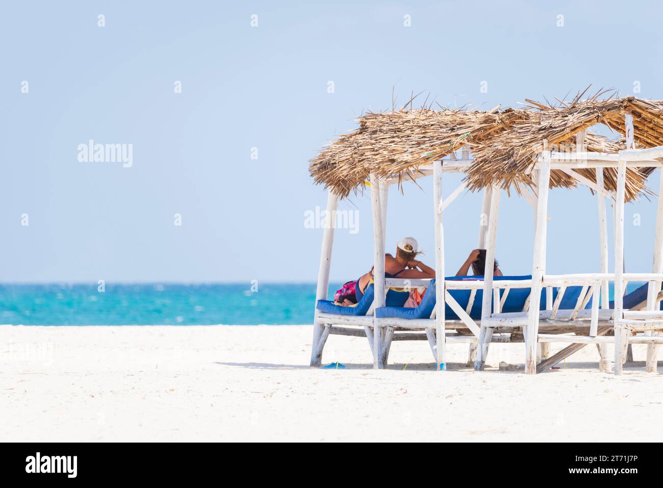 Coppia senior che si rilassa sulle sdraio della spiaggia. Spiaggia di sabbia bianca e oceano turchese, lussuosa casa sulla spiaggia. Foto Stock