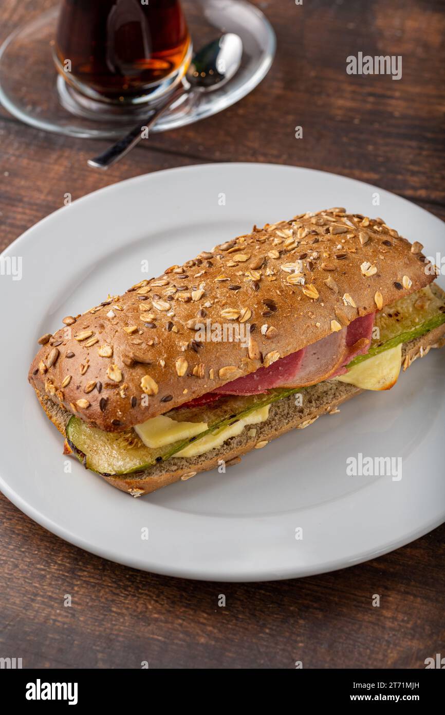 Sandwich con verdure e prosciutto e tè su un tavolo di legno Foto Stock