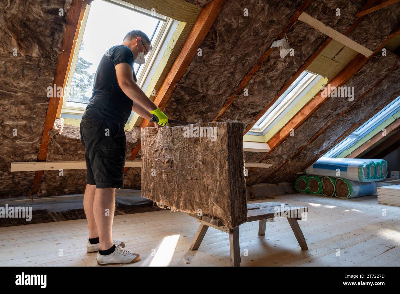 L'artigiano taglia il materiale isolante per isolare l'attico. Foto Stock