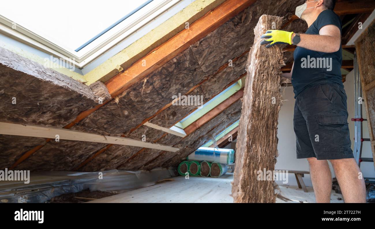 L'artigiano tiene il materiale isolante per isolare l'attico. Foto Stock