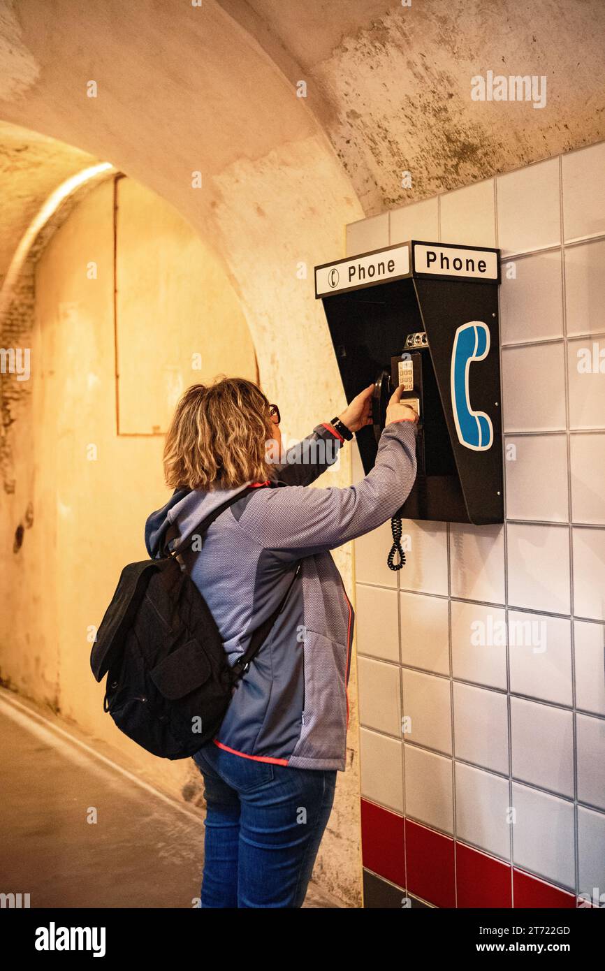 donna che usa un vecchio telefono pubblico a gettoni Foto Stock
