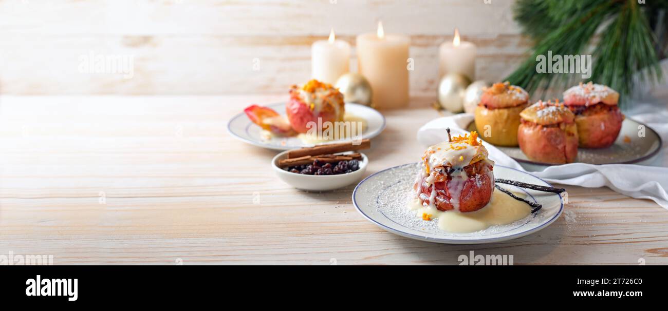 Mele al forno tedesche con zucchero in polvere e salsa alla vaniglia, ripiene di mandorle, miele e rosine su uno sfondo di legno chiaro, dessert natalizio, Foto Stock