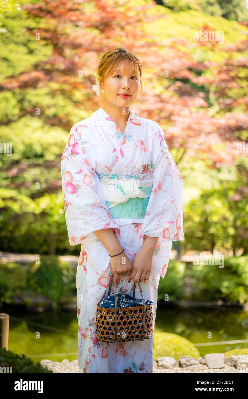 Ritratto di una giovane donna che indossa un kimono estivo yukata con sfondo morbido sfocato in un giardino giapponese. Kyoto, Giappone. Foto Stock