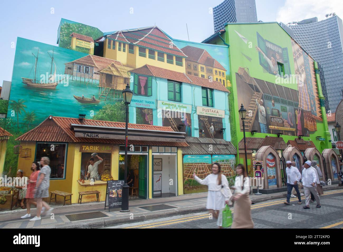 Un gruppo di persone ha camminato di fronte all'enorme e vivace murale di Street art che racconta diverse storie di Kampong Glam, Singapore Foto Stock