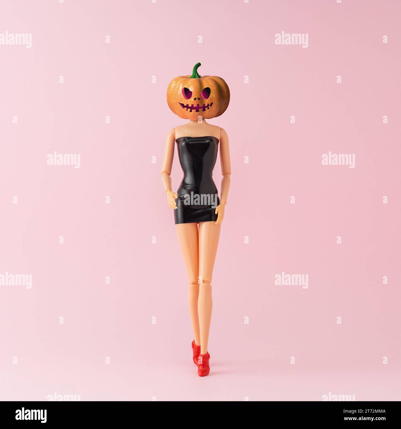 Bambola con testa di zucca. Concetto creativo di festa di Halloween. Arte di moda minimalista. Foto Stock