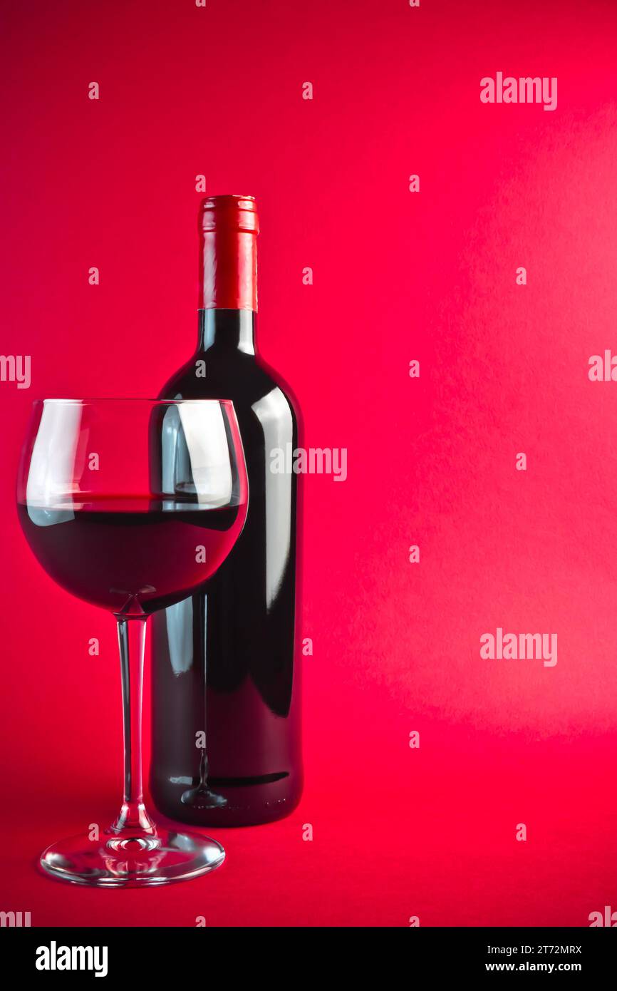 bottiglia con vino rosso e bicchiere su sfondo rosso Foto Stock