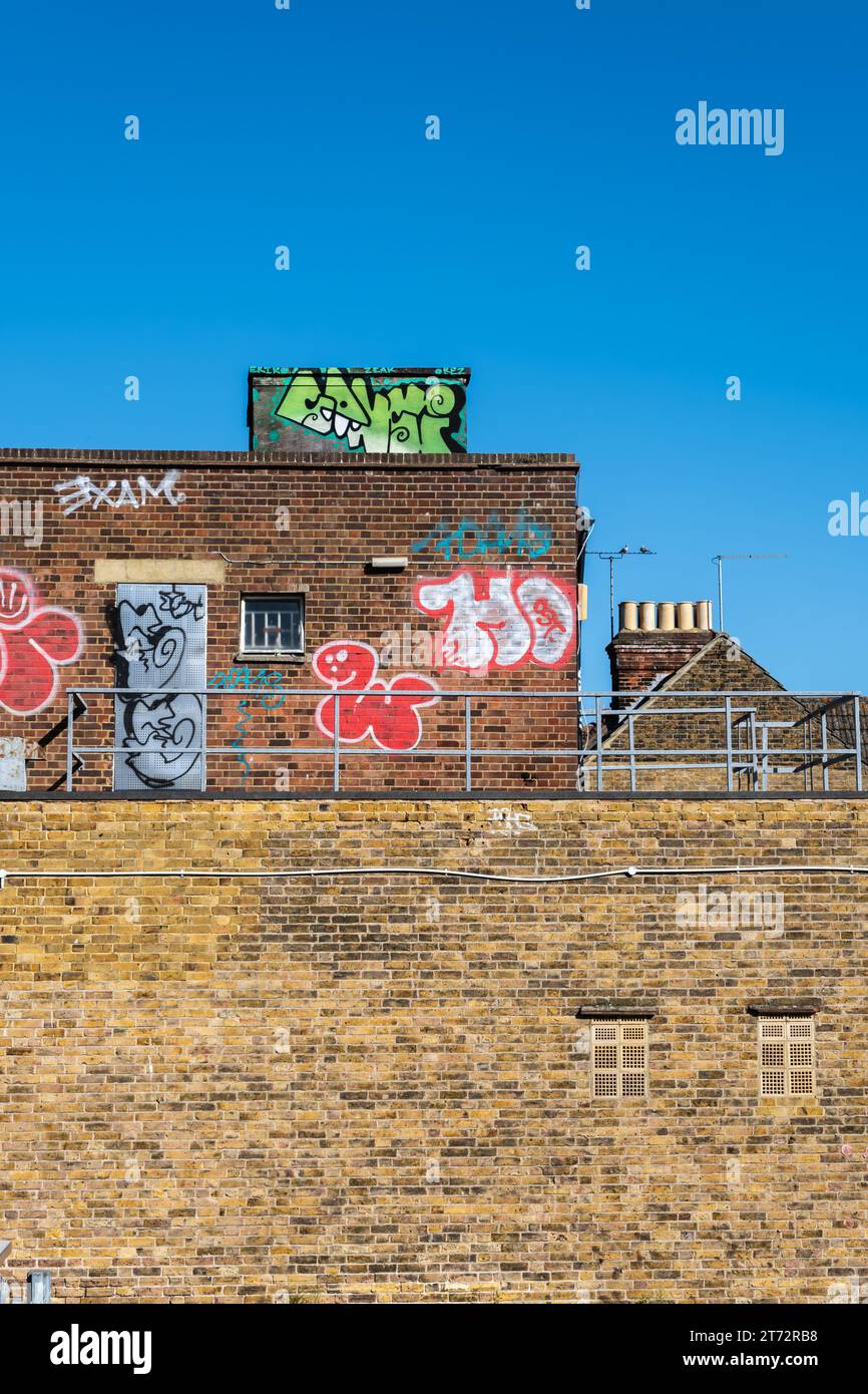 La parte superiore di un edificio in mattoni ricoperto di graffiti Foto Stock