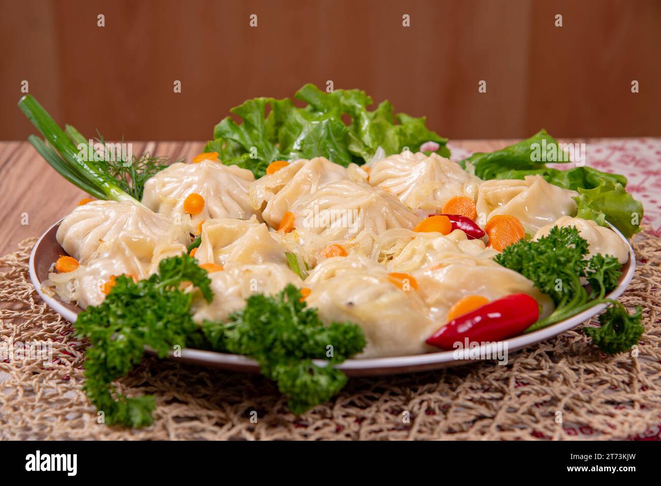 Manty (gnocchi di carne) è un piatto nazionale dei paesi dell'Asia centrale su un piatto con carote e verdure Foto Stock