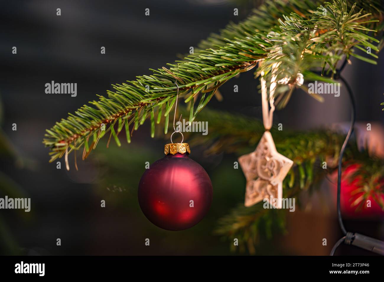 Una palla rossa e una stella su un albero di Natale tagliato per Natale Foto Stock